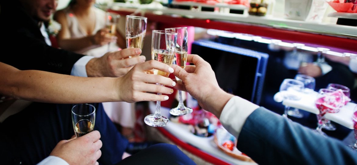 Groomsmen and bridesmaids drinking champagne in the limo.
